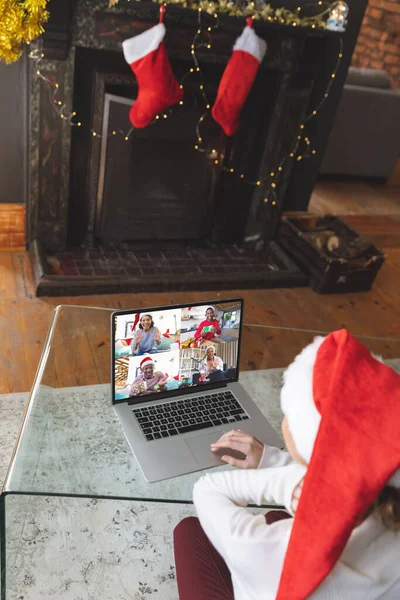 クリスマスのノートパソコンのビデオ通話を持つサンタの帽子を持つ白人女性幸せな多様な友人と クリスマス お祝いとデジタル複合画像 — ストック写真
