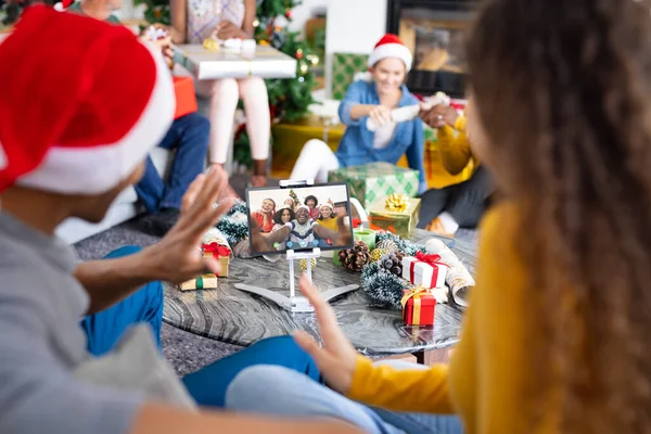 Diverse friends with christmas decorations having video call with happy diverse friends. Christmas, celebration and digital composite image.