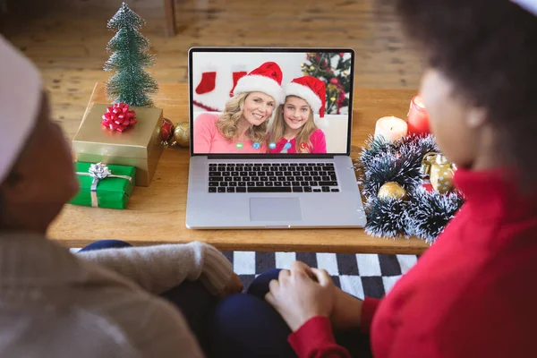 戴桑塔帽的非裔美国人家庭与快乐的高加索人家庭有视频通话 圣诞节 庆祝活动和数码合成图像 — 图库照片