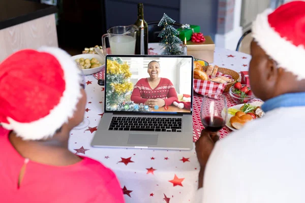 Kıdemli Afro-Amerikan çifti Afrikalı Amerikalı bir kadınla Noel 'de görüntülü görüşme yapıyor. İletişim teknolojisi ve noel, dijital kompozit görüntü.