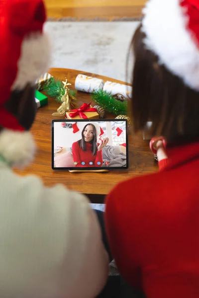 幸せな白人女性とビデオ通話を持つサンタの帽子を持つ多様なカップル クリスマス お祝いとデジタル複合画像 — ストック写真