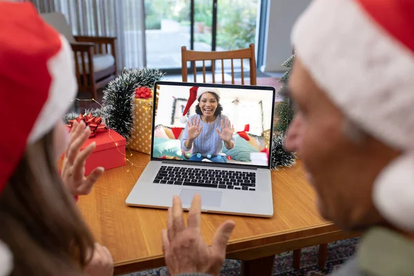 幸せな出産の女性とクリスマスのラップトップビデオ通話を持つサンタの帽子を持つ白人カップル クリスマス お祝いとデジタル複合画像 — ストック写真