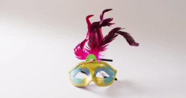 Sarı ve mavi maskeli, beyaz arka planda pembe tüylü, kopyalama alanı olan bir maske. Karnaval, kostüm, parti malzemeleri, eğlence ve kutlama konsepti..