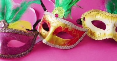 Pembe arka planda yeşil tüylü üç karnaval maskesi videosu. Karnaval, kostüm, parti malzemeleri, eğlence ve kutlama konsepti..