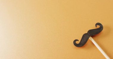 Sarı arkaplandaki sahte bıyıklı fotokopi alanı videosu. Babalar günü, kostüm, parti malzemeleri, eğlence ve kutlama konsepti..