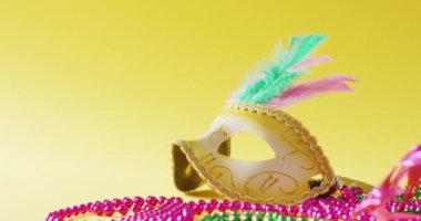 Tüylü maskeli maskeli ve sarı arkaplanlı mardi gras boncuklu fotokopi alanı. Karnaval, kostüm, parti malzemeleri, eğlence ve kutlama konsepti..