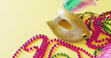 Tüylü maskeli maskeli ve sarı arkaplanlı mardi gras boncuklu fotokopi alanı. Karnaval, kostüm, parti malzemeleri, eğlence ve kutlama konsepti..