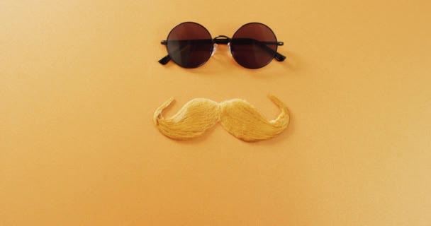 黄色の背景にブロンドの偽の口ひげと丸いサングラスのビデオ 父の日 ドレスアップ パーティーの小道具 楽しさとお祝いのコンセプト — ストック動画