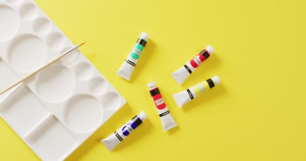 コピースペースと黄色の背景に水の色の塗料 絵筆やパレットのチューブのビデオ アート 創造性 工芸品 趣味の概念 — ストック動画