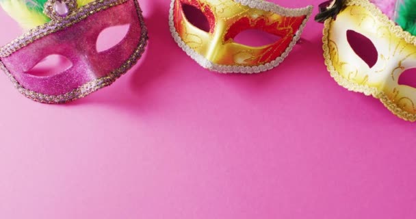 コピースペース付きピンクの背景に3つのピンクと金のカーニバル仮面のビデオ カーニバル ドレスアップ パーティーの小道具 楽しさとお祝いのコンセプト — ストック動画