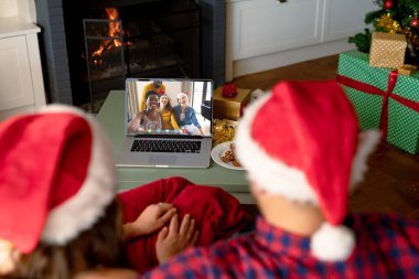 Noel Baba şapkalı beyaz çift farklı arkadaşlarıyla görüntülü görüşme yapıyor. Noel, kutlama ve dijital kompozit görüntü.