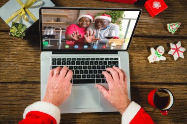 Noel hediyeli Noel Baba mutlu Afro-Amerikan çiftiyle görüntülü görüşme yapıyor. Noel, kutlama ve dijital kompozit görüntü.