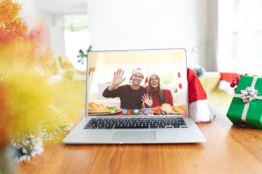 Beyaz bir çift dizüstü bilgisayar ekranında noel görüntüsü alıyor. İletişim teknolojisi ve noel, dijital kompozit görüntü.