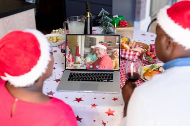 Kıdemli Afro-Amerikan çifti çeşitli insanlarla yılbaşı videosu çekiyor. İletişim teknolojisi ve noel, dijital kompozit görüntü.