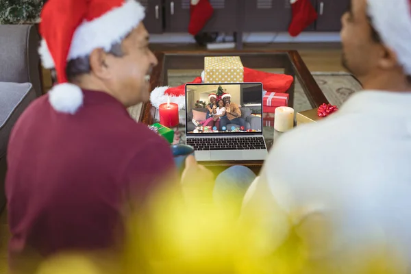 年长的白人男子和他的成年儿子与非洲裔美国家庭有圣诞视频通话 通信技术和圣诞节数字合成图像 — 图库照片