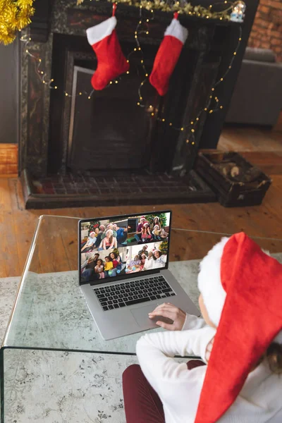 クリスマスのノートパソコンのビデオ通話を持つサンタの帽子を持つ白人女性幸せな多様な友人と クリスマス お祝いとデジタル複合画像 — ストック写真