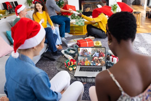 Diverse friends with christmas decorations having video call with happy diverse friends. Christmas, celebration and digital composite image.