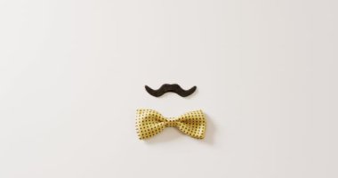 Siyah sahte bıyıklı ve sarı benekli papyonlu beyaz arka planda fotokopi alanı olan bir video. Babalar günü, kostüm, parti malzemeleri, eğlence ve kutlama konsepti..