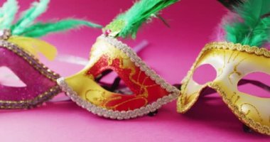 Pembe arka planda yeşil tüylü üç karnaval maskesi videosu. Karnaval, kostüm, parti malzemeleri, eğlence ve kutlama konsepti..