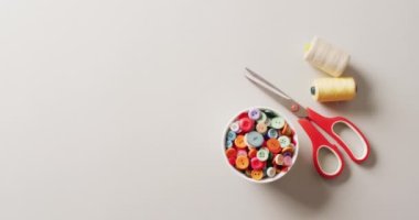 Bir kase düğmeli makas videosu ve beyaz zemin üzerinde fotokopi alanı olan iplik makarası. Dikiş dikme, terzilik, yaratıcılık, el işleri ve hobiler konsepti.