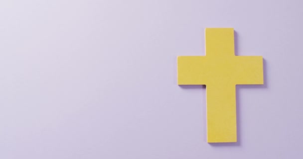 コピースペースとライラックの背景に黄色のキリスト教の十字架記号のビデオ キリスト教 お祝いの概念 — ストック動画