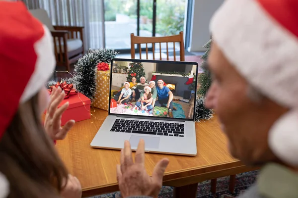 Caucasian father and daughter having christmas video call with caucasian family. Communication technology and christmas, digital composite image.