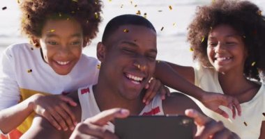 Afrika kökenli Amerikan ailesinin sahilde selfie çekmesi üzerine yılbaşı konfetisinin animasyonu. Noel, gelenek, kutlama ve şenlik kavramı dijital olarak oluşturuldu.