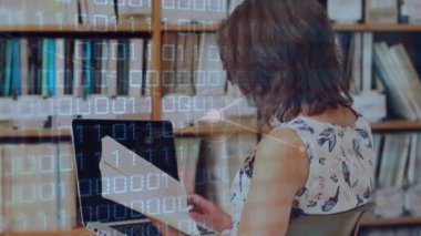 Genç bir kadın üniversitede dizüstü bilgisayarla kütüphanede okuyor.. 