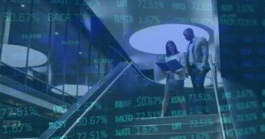 İki iş adamı konuşuyor ve modern bir ofisin merdivenlerinden aşağı iniyorlar. İş konularını tartışıyor ve sonraki adımlarını planlıyorlar. Bu arada, dijital ekranda mali veriler ve grafikler gösteriliyor.  