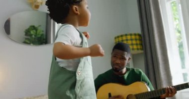 Mutlu Afro-Amerikan baba ve oğlunun gitar çalması üzerine parlayan ışığın animasyonu. Aile, ebeveynlik, müzik ve birlikte zaman geçirme konsepti dijital olarak oluşturulmuş video.