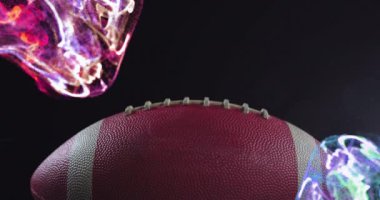 Rugby topu üzerinde siyah arkaplana karşı mercek fişeği ve çok renkli soyut desen animasyonu. Dijital bileşik, çoklu pozlama, aydınlatma, spor, ışık ve rekabet konsepti.