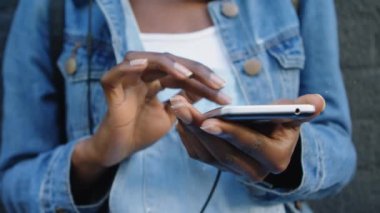 Cep telefonu kullanan Afrikalı Amerikalı bir kadının orta kesiminde kar yağışı animasyonu. Dijital bileşik, çoklu pozlama, kış, hava durumu, ceket ve kablosuz teknoloji kavramı.