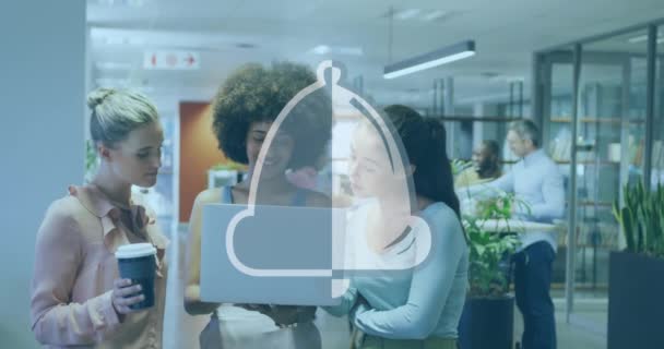 オフィスのラップトップ上で議論する多様な女性の同僚の上に鐘のアイコンのアニメーション ソーシャルメディアネットワークとビジネステクノロジーの概念 — ストック動画