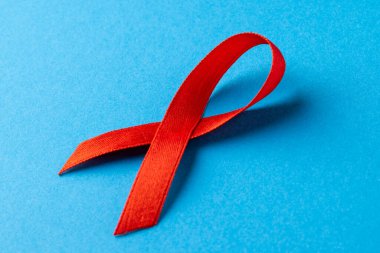 Mavi arkaplanda kırmızı kurdelenin bileşimi. Tıp, sağlık, bilim ve kopyalama alanı konsepti, dijital kompozit resim.