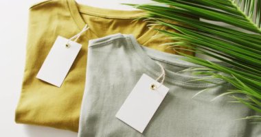 Katlanmış yeşil ve hardallı tişörtlerin beyaz arkaplan etiketli videosu. Giyim, moda, perakende, kumaş, doku ve malzeme konsepti.