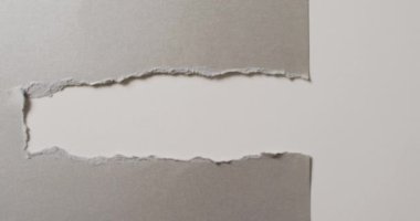 Beyaz arka planda yırtık gri kağıtların yakın çekim videosu. Kağıt, yazı, doku ve malzeme kavramı.