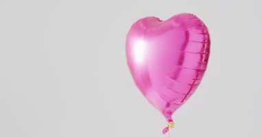 Beyaz zemin üzerinde yüzen parlak pembe kalp şekilli balon videosu, fotokopi alanı ile. Sevgililer Günü, aşk, aşk ve kutlama konsepti.