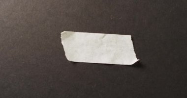 Siyah arka planda beyaz bant parçasının yakın çekim videosu. Kağıt, yazı, doku ve malzeme kavramı.