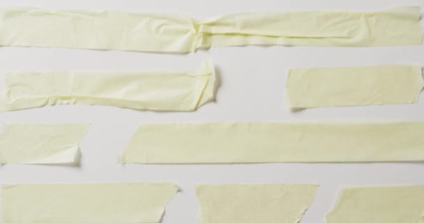 白い背景にコピースペースと黄色の紙の複数の引き裂かれた部分のクローズアップのビデオ 素材のコンセプト — ストック動画