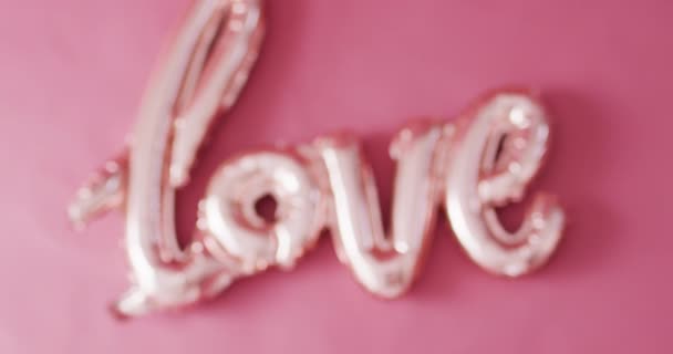 コピースペース付きピンクの背景に光沢のある淡いピンクの愛のテキストバルーンのラックフォーカスビデオ バレンタインデー ロマンス 愛とお祝いのコンセプト — ストック動画