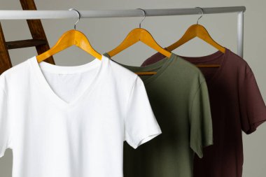 Merdivende gösterilen renkli tişörtler ve beyaz arkaplanda kopyalama alanı. Giyim, moda ve perakende konsepti.