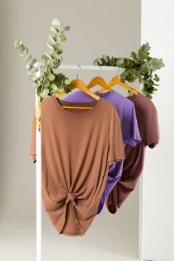 Giysi demiryollarında sergilenen tişörtler ve beyaz arka planda fotokopi alanı. Giyim, moda ve perakende konsepti.