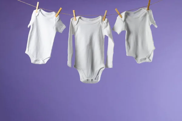 Ropa Bebé Colgando Una Cuerda Espacio Copia Sobre Fondo Púrpura —  Fotos de Stock