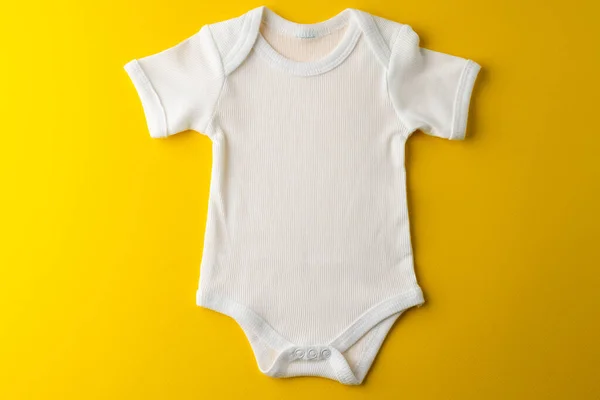 黄色の背景に赤ちゃんの白いTシャツを閉じます 衣類やアクセサリー 新生児や幼児の育児の概念 — ストック写真