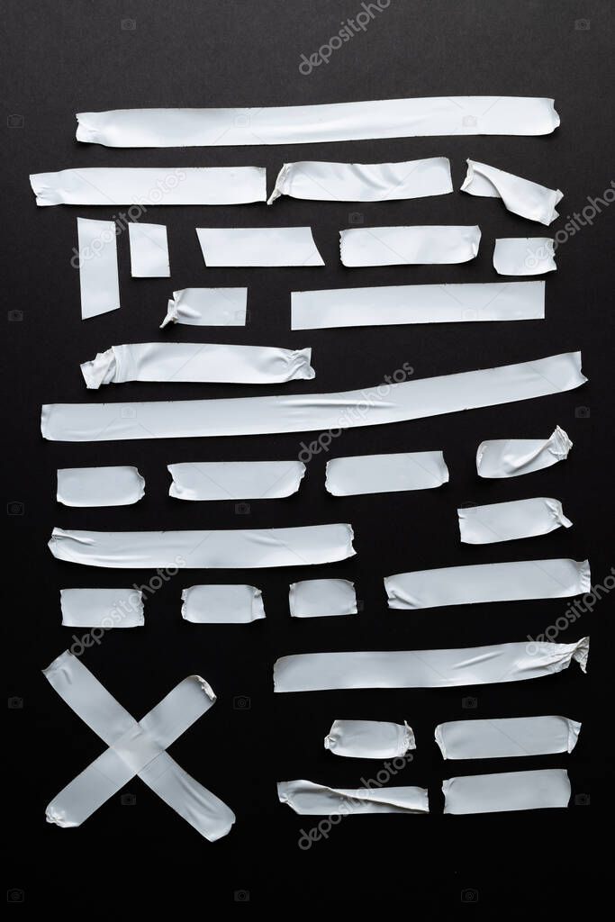 Ripped up pieces of white tape with copy space on black background. Abstract paper texture background and communication concept.