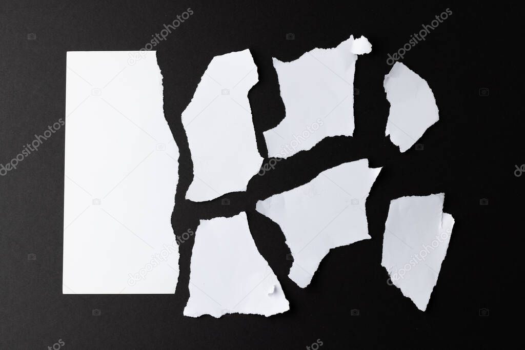 Ripped up pieces of white paper with copy space on black background. Abstract paper texture background and communication concept.