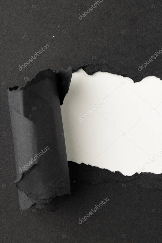 Ripped up piece of black paper with copy space on white background. Abstract paper texture background and communication concept.