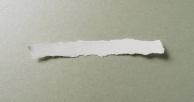 Yeşil arka planda yırtık beyaz kağıt parçasının yakın çekim videosu. Kağıt, yazı, doku ve malzeme kavramı.