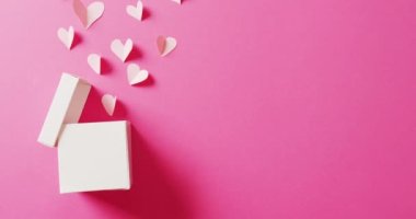 Beyaz hediye kutusu videosu ve beyaz kağıt kalp şekilleri, pembe arka planda fotokopi alanı ile. Sevgililer Günü, aşk, aşk ve kutlama konsepti.