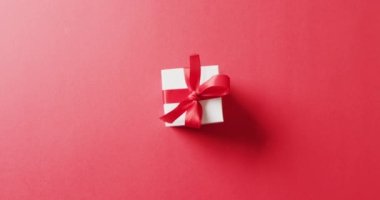 Kırmızı pruvayla bağlanmış beyaz hediye kutusunun kırmızı arka planda fotokopi alanı olan videosu. Sevgililer Günü, aşk, aşk ve kutlama konsepti.